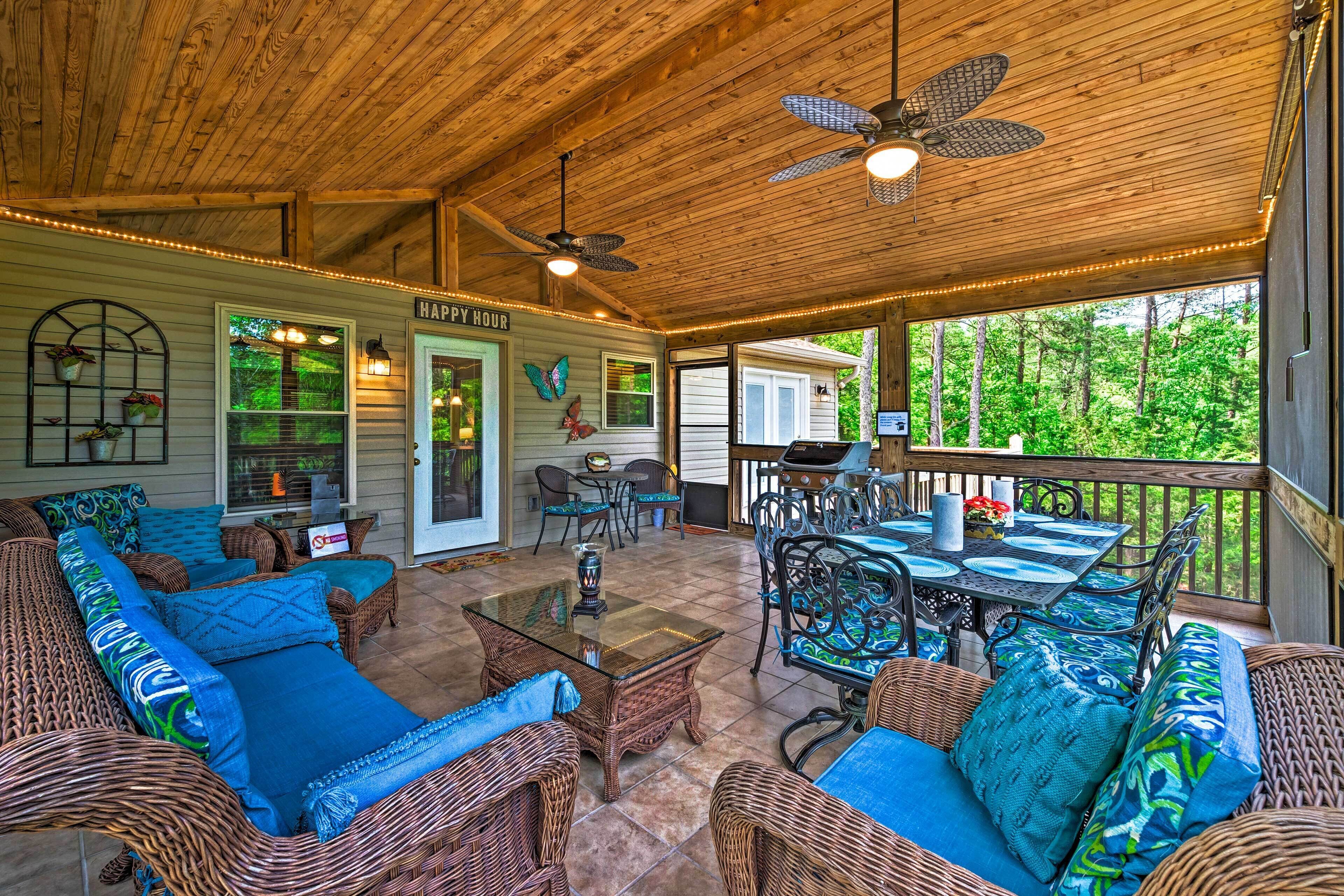 A covered patio area with wicker furniture, a dining table, and ceiling fans.