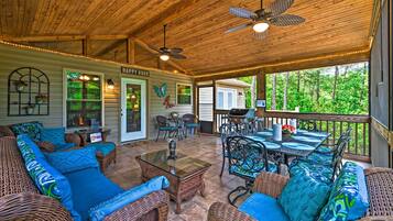 A covered patio area with wicker furniture, a dining table, and ceiling fans.
