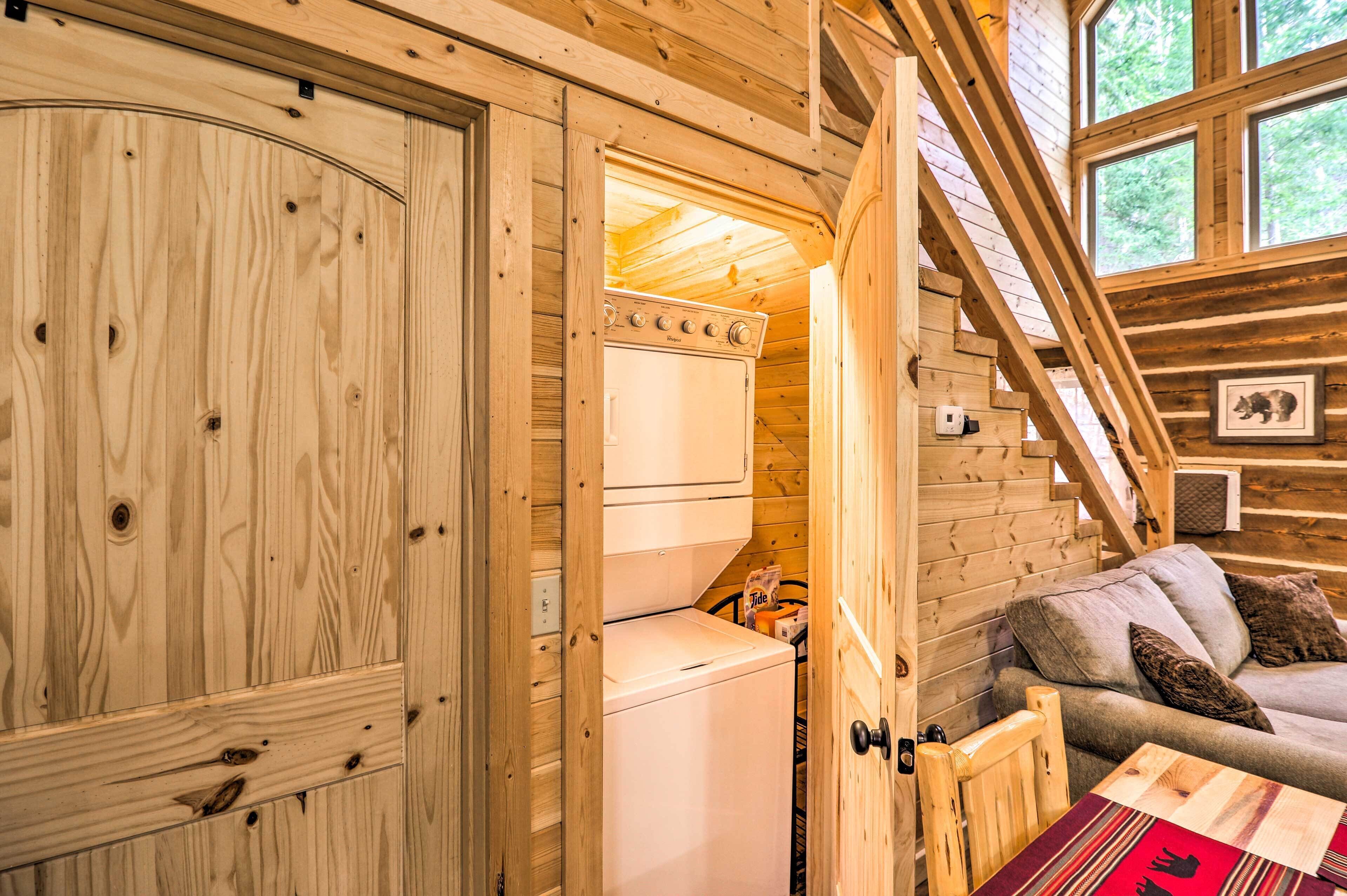 A wooden cabin interior with a washing machine, a sofa, and a staircase.