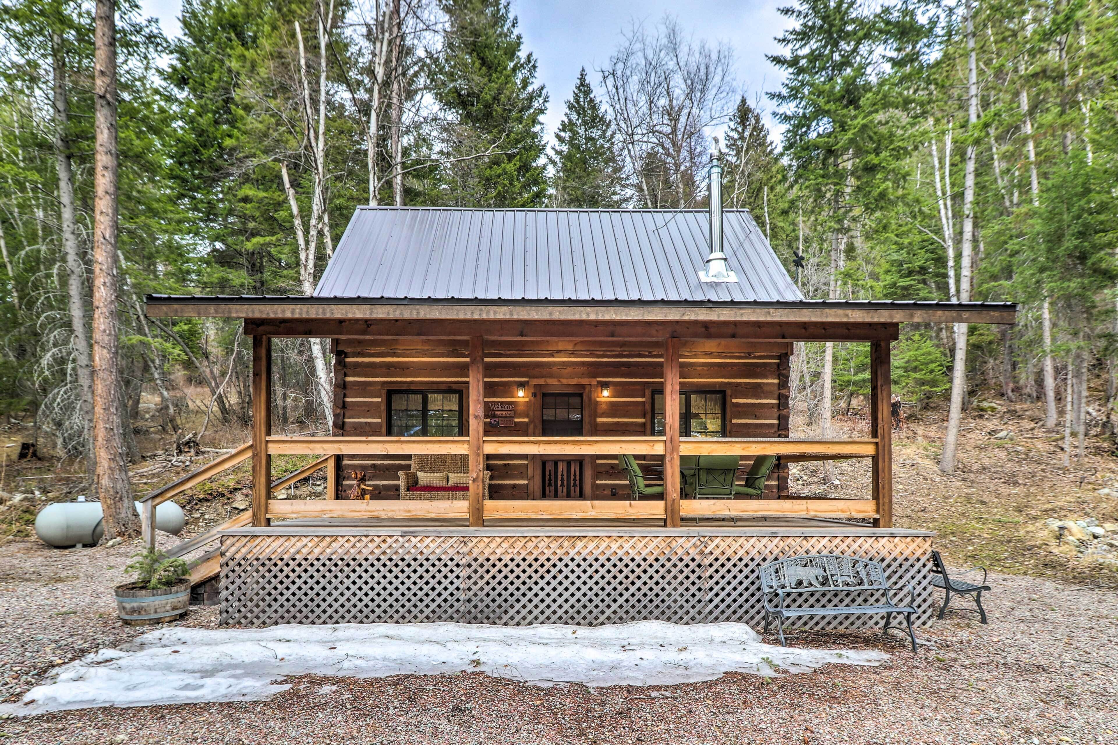 A log cabin with a porch, wooden deck, and a metal roof.