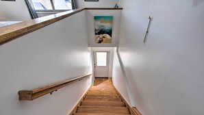 Eine Holztreppe mit Handlauf, die zu einer Tür oben führt.
