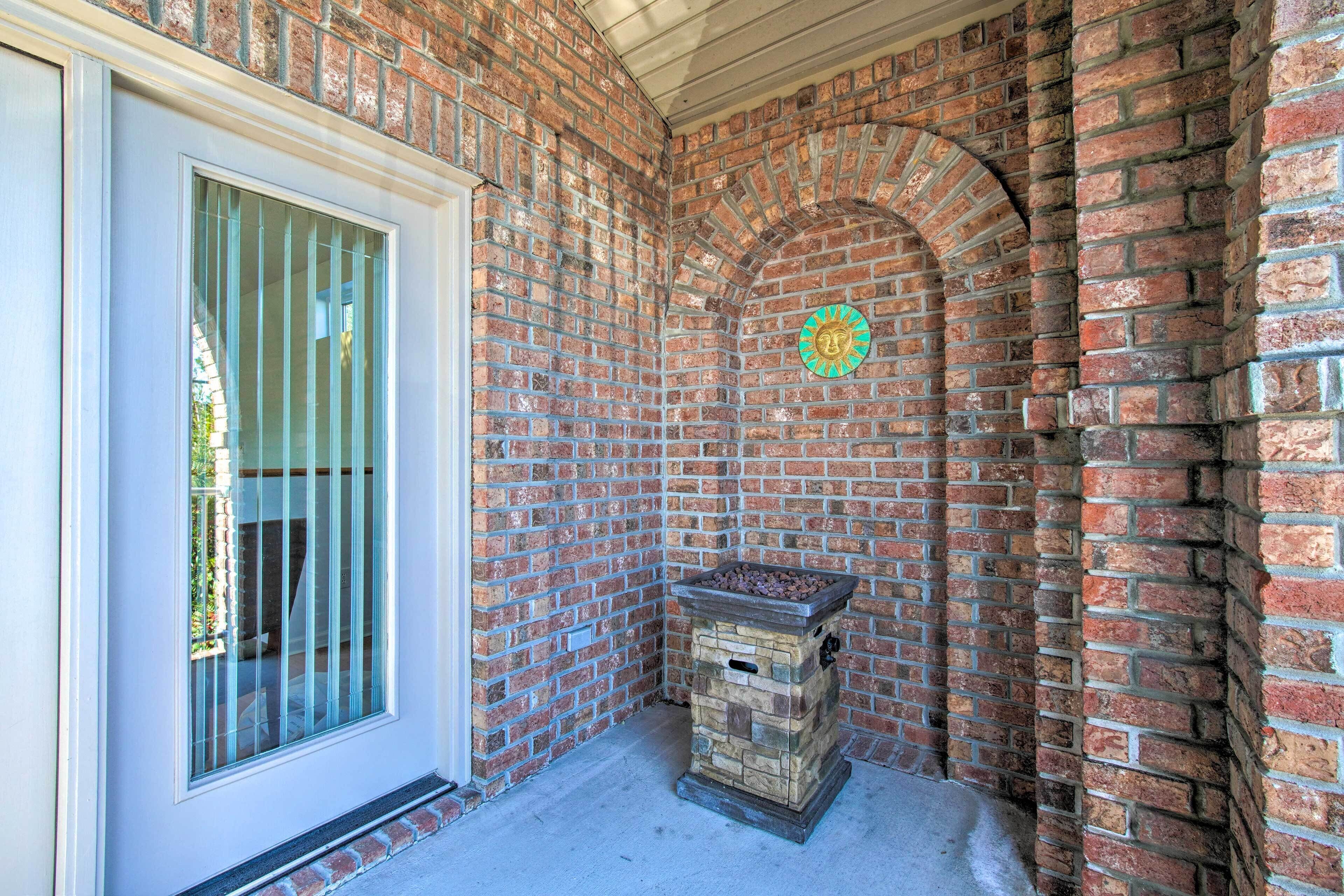 A corner of a building with a brick wall, a window with metal bars, and a stone fireplace.