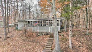 A cabin with a porch, surrounded by trees and a wooden staircase leading up to it. - Athens Vintage Fishing Cabin on Elk River! (Athens)