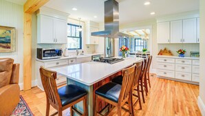 A spacious kitchen with white cabinets, a large island with bar stools, a stainless steel range hood, and wooden flooring. - Stunning Damascus Vacation Rental w/ Fire Pit! (Damascus)
