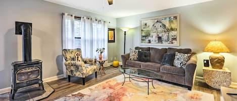 Una sala de estar con sofá, sillón, mesa de centro y chimenea.