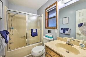 A bathroom with a glass-enclosed shower, a toilet, and a sink with a mirror.