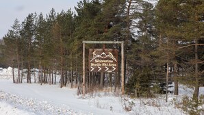 A sign for Wolverine Nordic Ski Area surrounded by snow and trees.