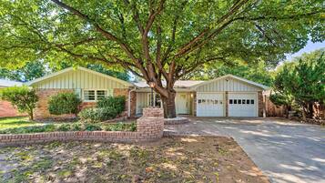 Set amidst a lush garden, this two-story house offers an entrance and attached garage.