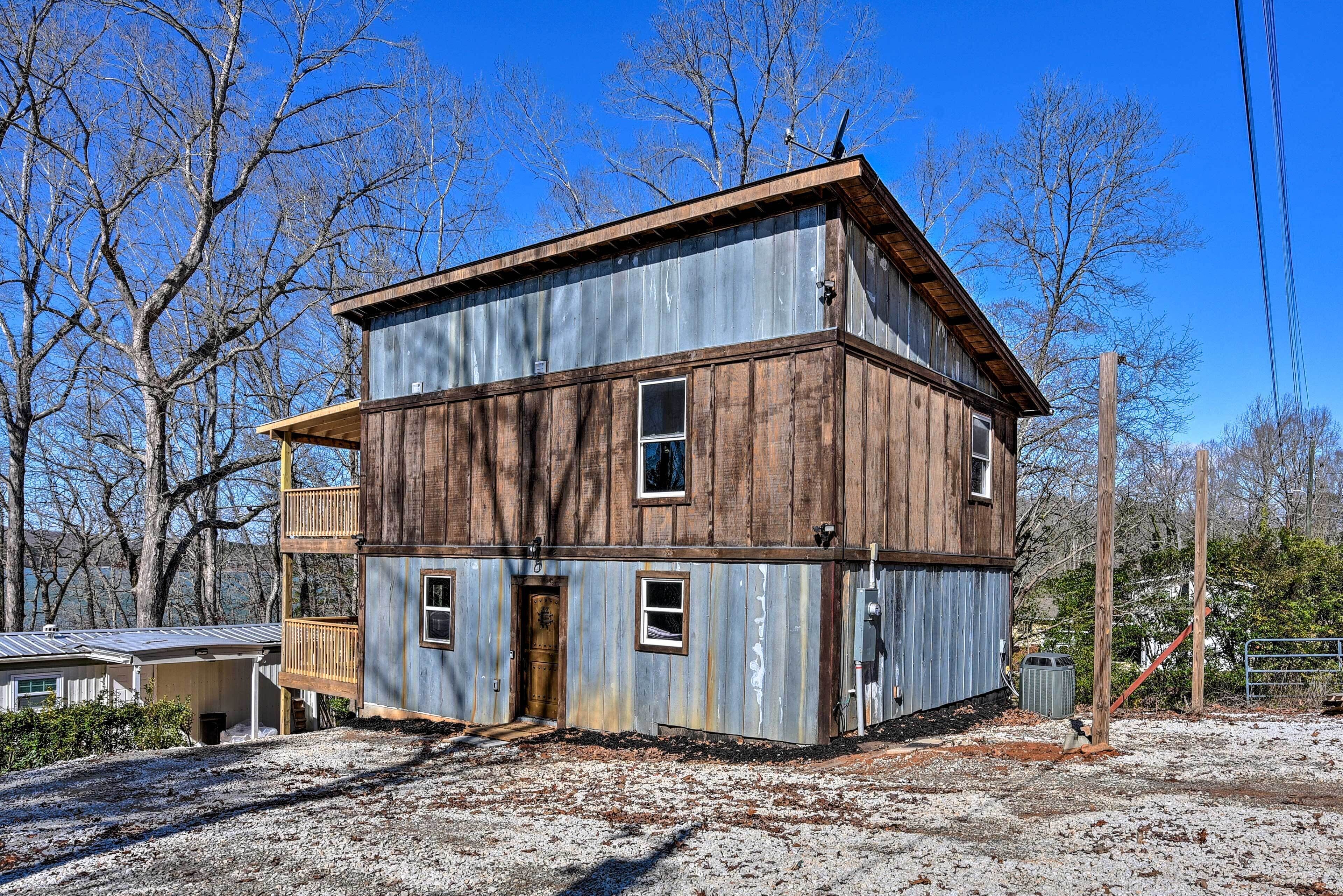 A two-story building with a wooden exterior and a metal roof, surrounded by trees and a clear sky.