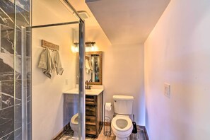 Une salle de bain avec une douche à parois de verre, un meuble-lavabo en bois avec un miroir et des toilettes.