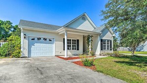 A single-story house with a garage, a front porch, and a small garden area. - Cozy Wilmington Bungalow ~ 6 Mi to Beaches! (Wilmington)