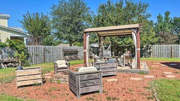 A backyard with a wooden pergola, outdoor seating, and a fire pit area. - Cozy Wilmington Bungalow ~ 6 Mi to Beaches! (Wilmington)