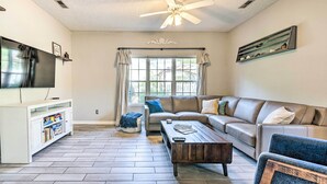A living room with a sofa, coffee table, TV, and a ceiling fan. - Cozy Wilmington Bungalow ~ 6 Mi to Beaches! (Wilmington)