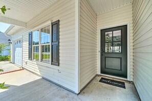 A house with a dark front door, a garage door, and a welcome mat. - Cozy Wilmington Bungalow ~ 6 Mi to Beaches! (Wilmington)