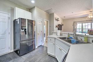 A modern kitchen with white cabinetry, a stainless steel refrigerator, a built-in sink, and a window providing natural light. - Cozy Wilmington Bungalow ~ 6 Mi to Beaches! (Wilmington)