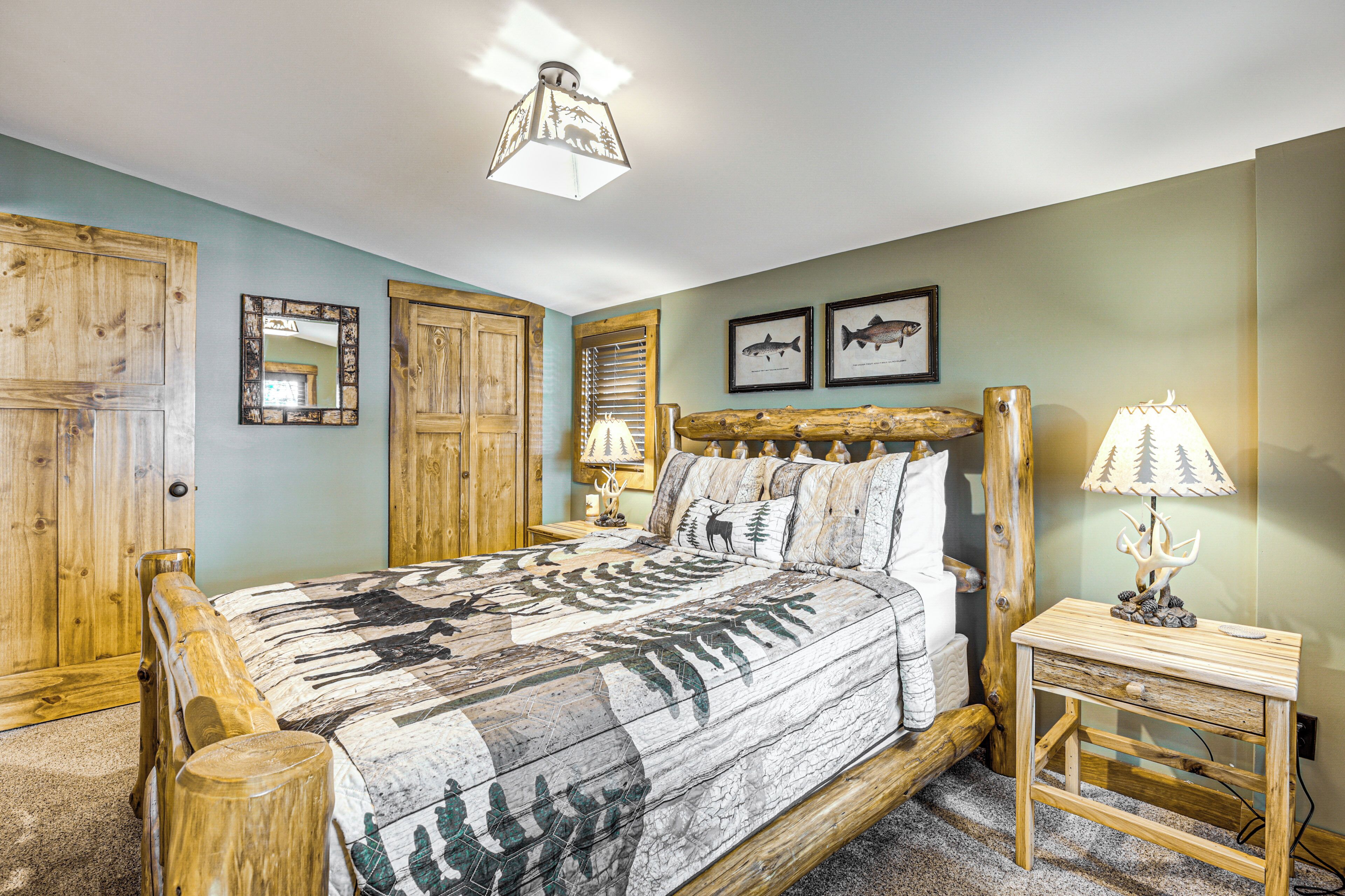 A bedroom with a large bed, wooden headboard, two bedside tables with lamps, a mirror, and framed fish pictures on the wall.