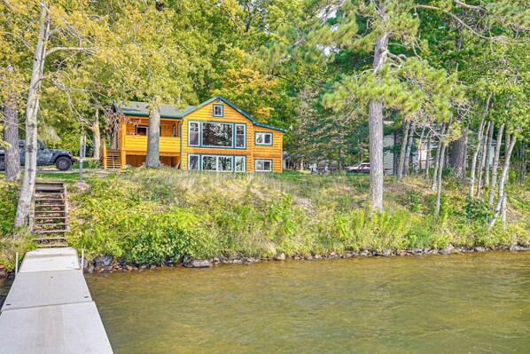 A wooden house with a green roof, situated by a river. - Quiet Lakefront Conover Cabin Near ATV Trails (Conover)