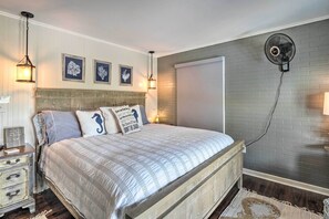 A bedroom with a large bed, a wooden headboard, a wall-mounted fan, and framed artwork on the wall. - Chic Family-friendly Home With Outdoor Oasis! (Lampasas)