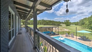 A wooden deck with a view of a swimming pool and outdoor seating area. - Chic Family-friendly Home With Outdoor Oasis! (Lampasas)