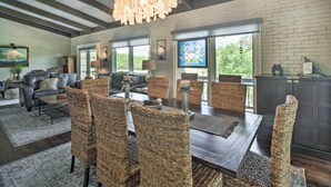 A spacious living room with a dark wooden dining table, wicker chairs, and a large chandelier. - Chic Family-friendly Home With Outdoor Oasis! (Lampasas)