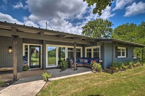 A house with a covered porch, a brick exterior, and a flag outside. - Chic Family-friendly Home With Outdoor Oasis! (Lampasas)