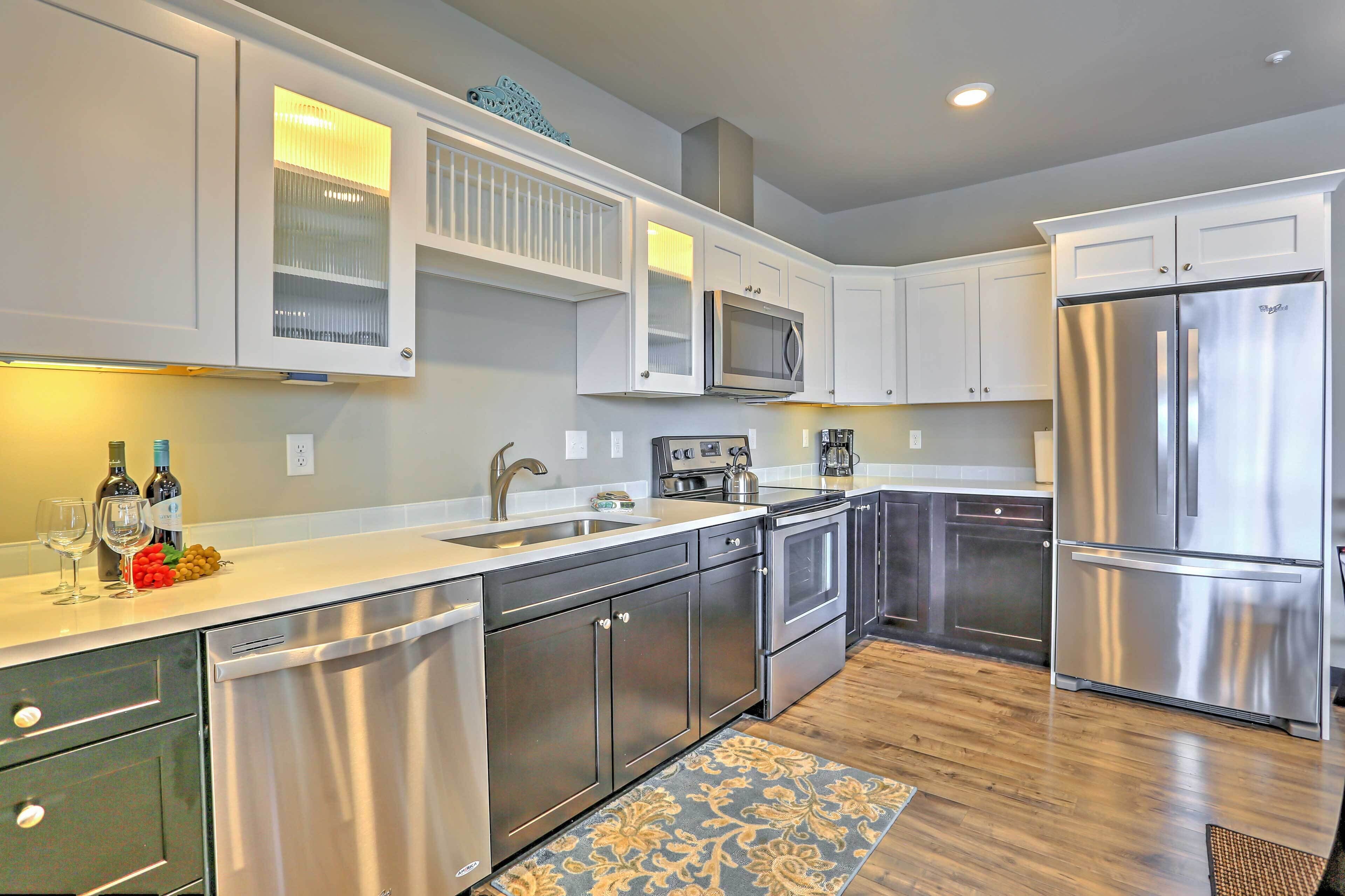 A modern kitchen with stainless steel appliances, white cabinetry, and a wooden floor.