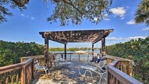 Eine Holzterrasse mit Liegestühlen und einer Pergola mit Blick auf ein Gewässer.