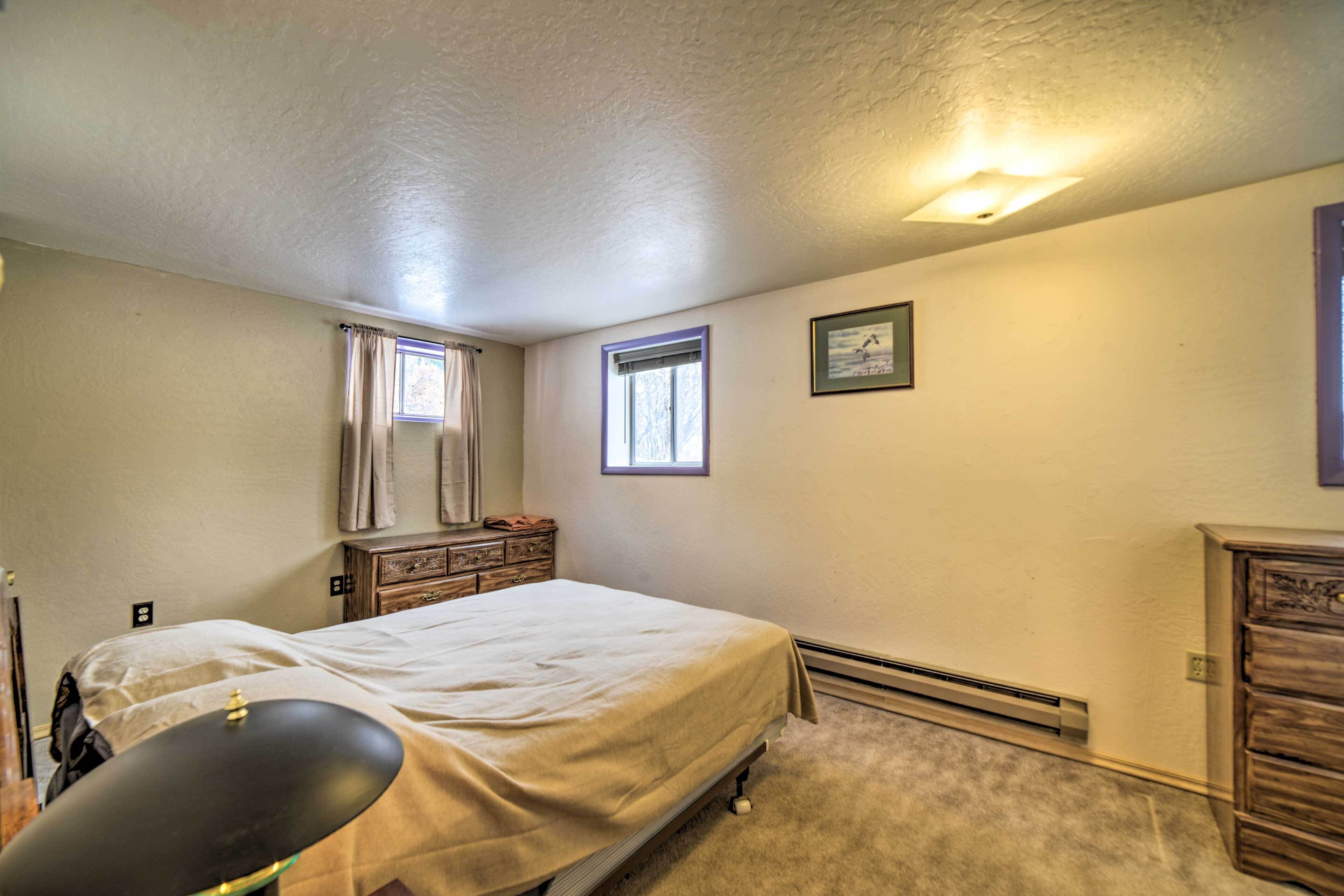 A bedroom with a bed, a dresser, a chair, a window, and a picture on the wall.