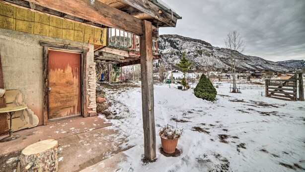 Una casa di legno rustica con un paesaggio innevato e montagne sullo sfondo.