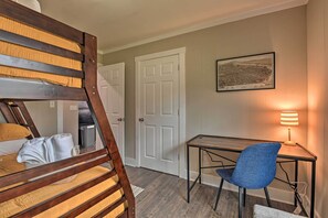Une chambre avec un lit superposé, un bureau avec une chaise, une lampe et une carte encadrée accrochée au mur.