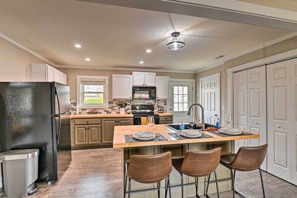 A modern kitchen with a central island, stainless steel appliances, and a dining area with bar stools. - Cozy Murfreesboro Home w/ Furnished Patio! (Murfreesboro)
