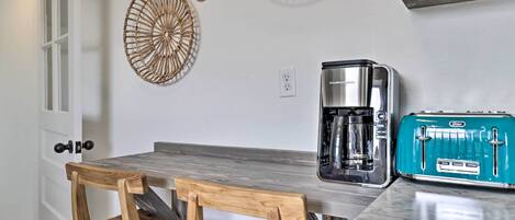 A kitchen with a wooden table, a coffee maker, and a vintage toaster.