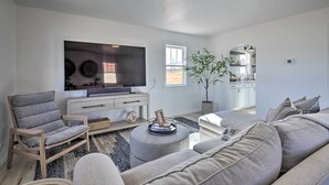 A modern living room with a grey sofa, a wooden chair, a TV, and a potted plant. - Modern Kanab Cottage w/ View < 1 Mi to Hiking! (Kanab)