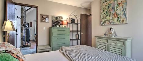 A bedroom with a bed, a green dresser, a nightstand, and a painting on the wall.