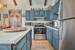 A kitchen with blue cabinets, stainless steel appliances, and a large painting on the wall. - Cozy Wintergreen Cabin Near Mountain Inn & Slopes! (Nellysford)