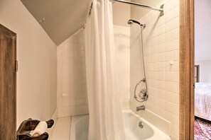 Une salle de bain avec une baignoire, une douche et une porte en bois.