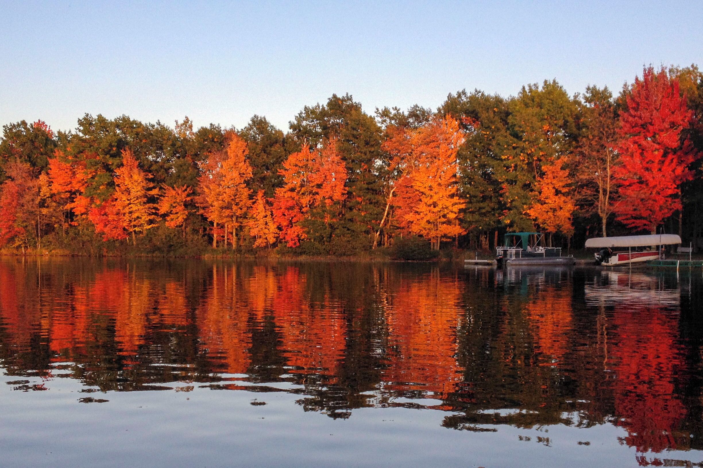 A calm lake with autumn-colored trees reflecting on the water.