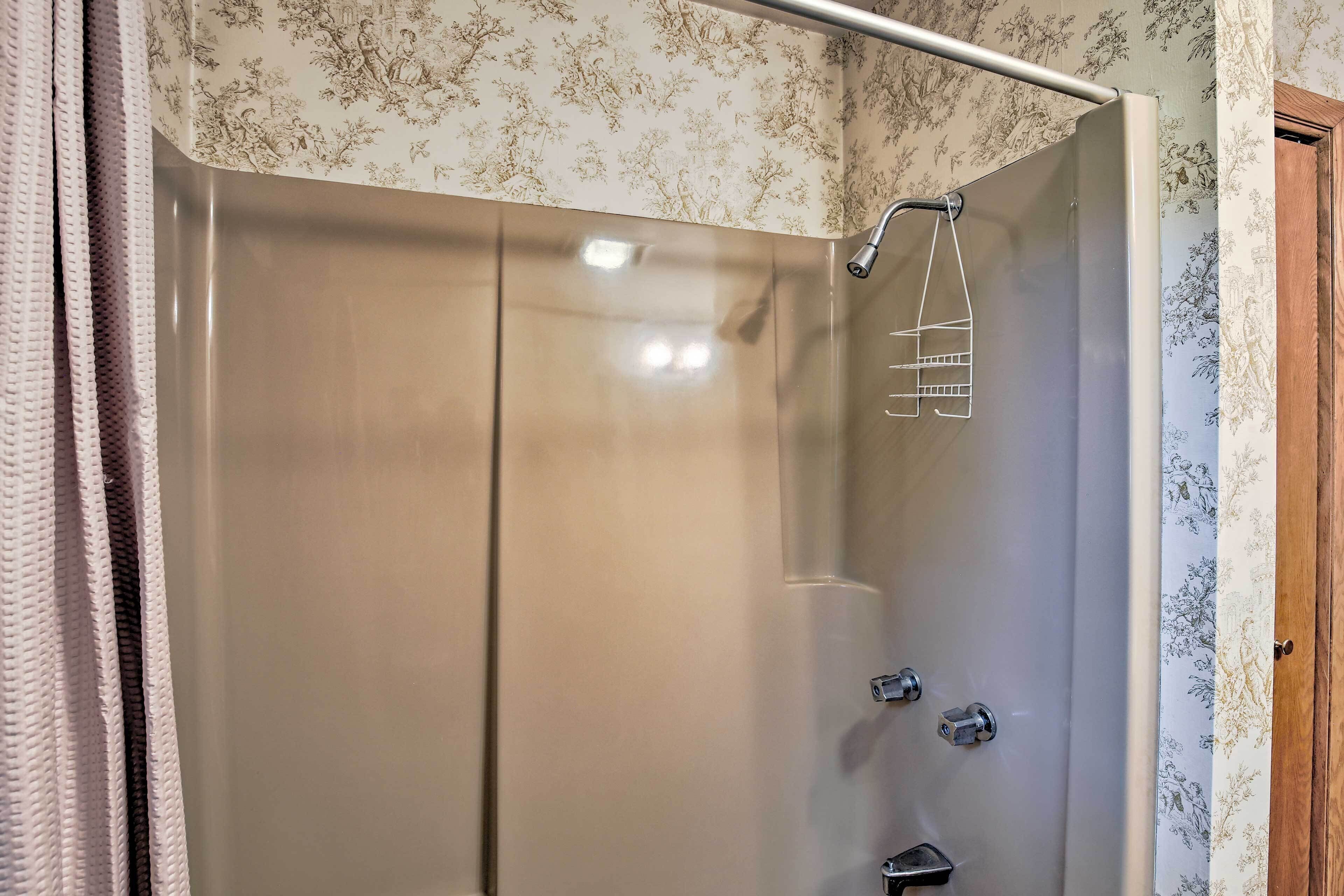 A modern bathroom with a glass shower enclosure, a handheld showerhead, and a towel rack.