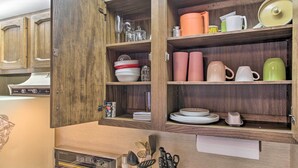 Una cocina con armarios de madera, estufa y diversos utensilios de cocina.
