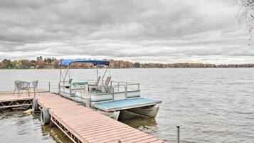 A wooden dock extending into a lake with a boat docked at the end.