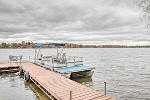 A wooden dock extending into a lake with a boat docked at the end.