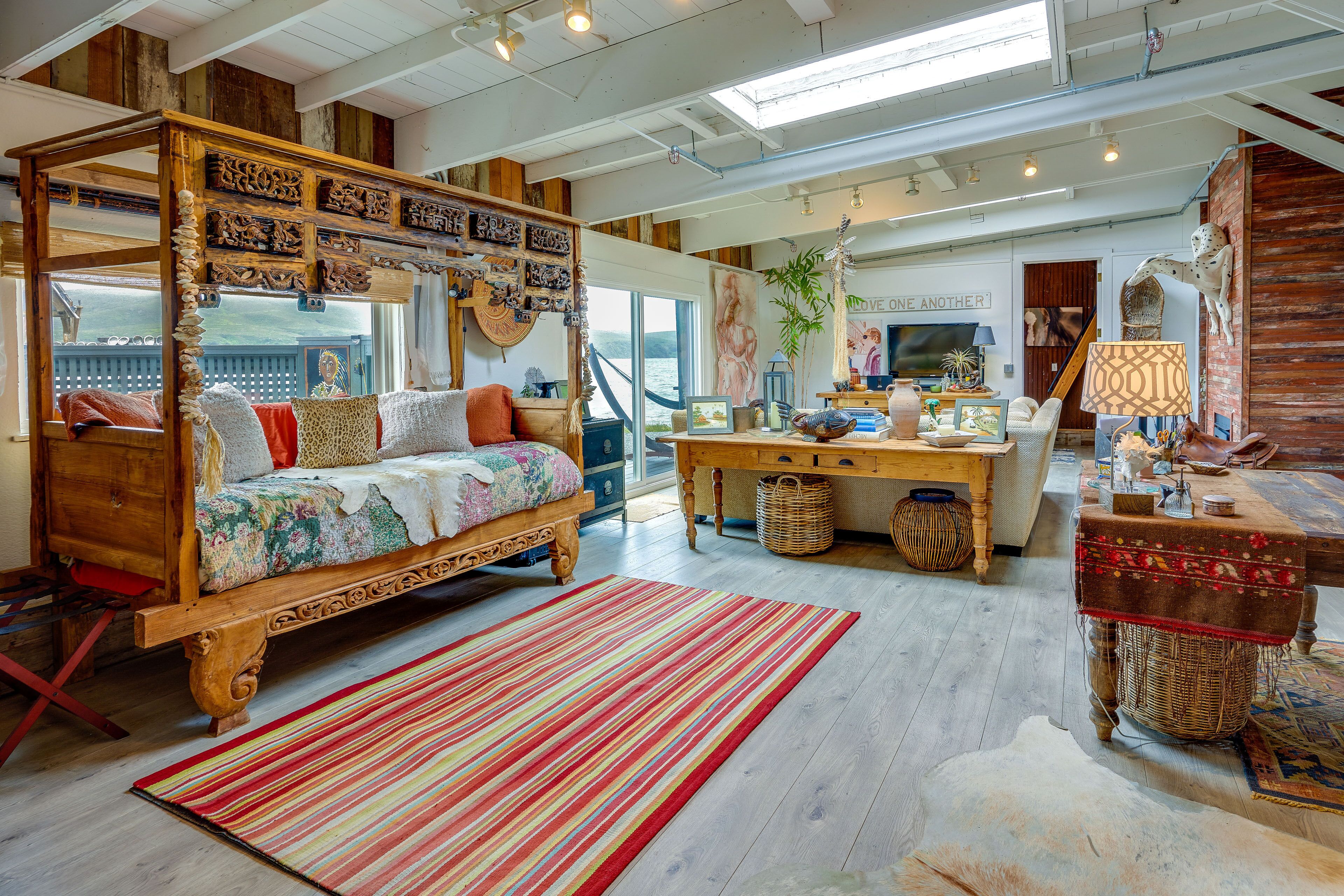 A cozy, rustic bedroom with a four-poster bed, a wooden desk, and a view of the outdoors.