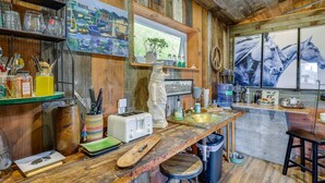 A rustic kitchen with wooden walls, a wooden countertop, a sink, and a window with a view of horses.