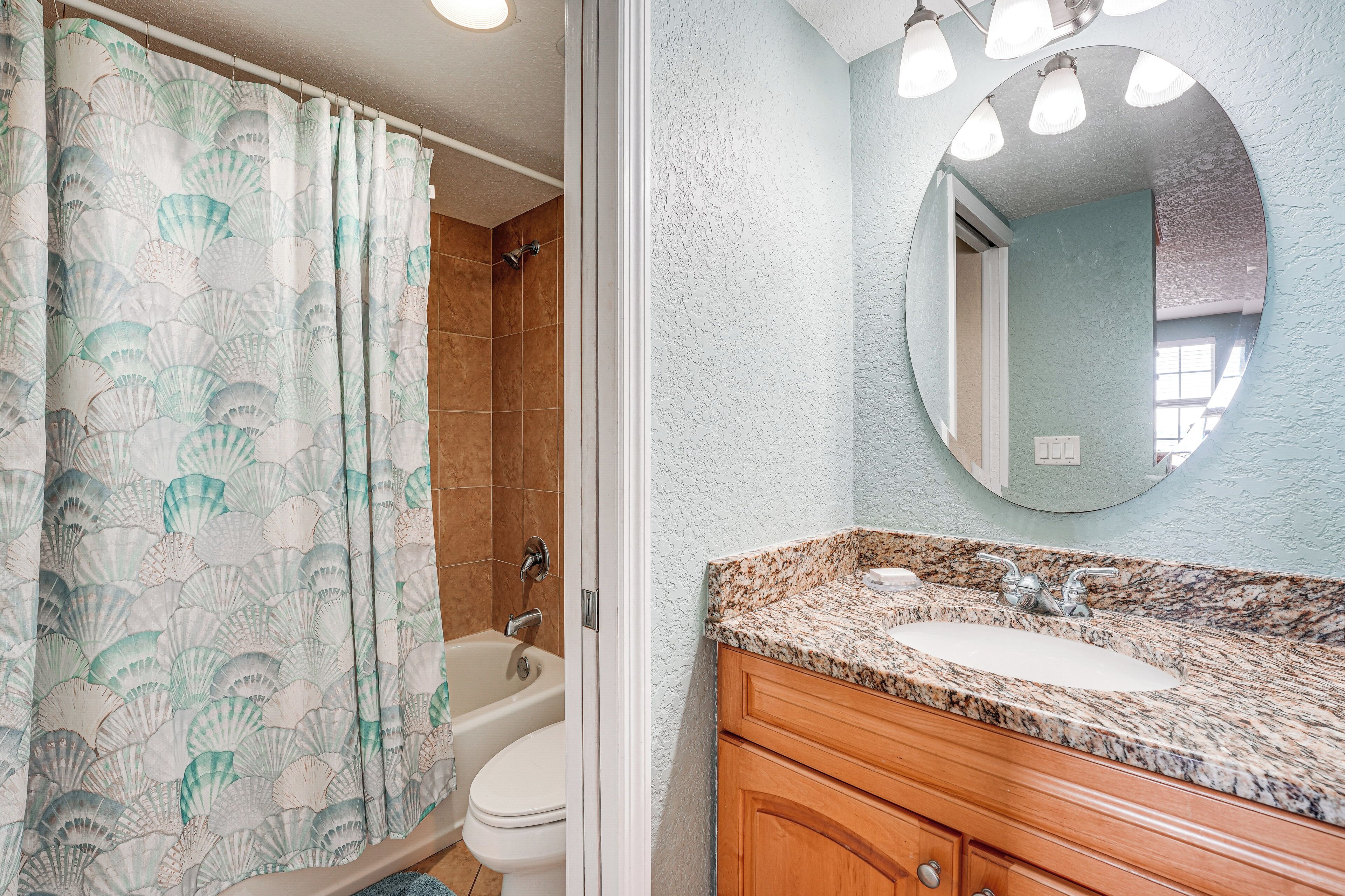 A bathroom with a shower, toilet, and sink with a mirror.