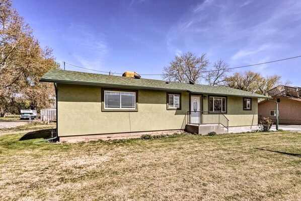 A single-story house with a green roof, a front porch with a small set of stairs, and a garage in the background. - Picturesque Palisade Home: Mt Garfield Views! (Palisade)