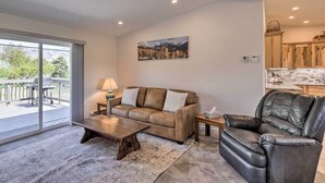 A living room with a sofa, coffee table, and leather armchair, a dining area with a table and chairs, and a kitchen with wooden cabinets. - Picturesque Palisade Home: Mt Garfield Views! (Palisade)