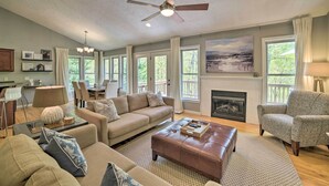 A spacious living room with a fireplace, a ceiling fan, and large windows. - Massanutten Family Retreat: Ski, Golf, & Hike! (McGaheysville)