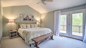 A bedroom with a bed, bedside lamps, a bench, a ceiling fan, and a large window with a view of the outdoors. - Massanutten Family Retreat: Ski, Golf, & Hike! (McGaheysville)