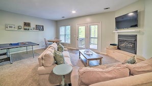 A living room with a sofa, coffee table, and fireplace. There is a television mounted above the fireplace and a table with chairs. - Massanutten Family Retreat: Ski, Golf, & Hike! (McGaheysville)