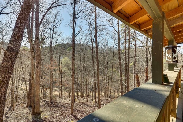 A wooden deck overlooking a forested area with bare trees. - Cute Eureka Springs Vacation Rental With Fire Pit! (Eureka Springs)